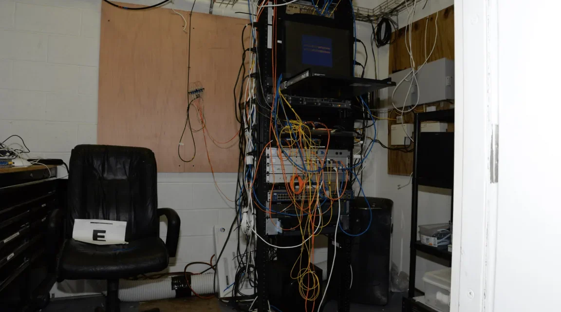 Rack de servidores con cables enmarañados en un cuarto técnico doméstico, imagen generada que ilustra el tipo de home lab descrito en el artículo